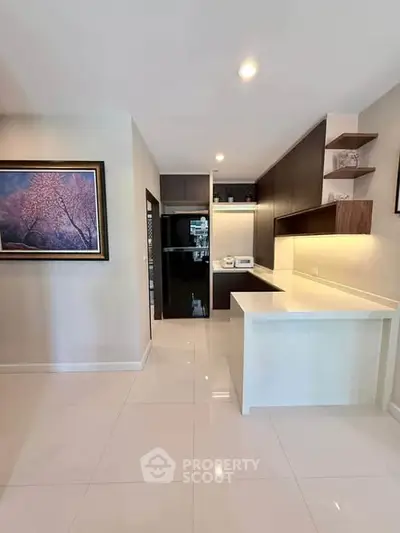 Modern kitchen with sleek cabinetry and open layout, featuring a stylish black fridge and elegant wall art.