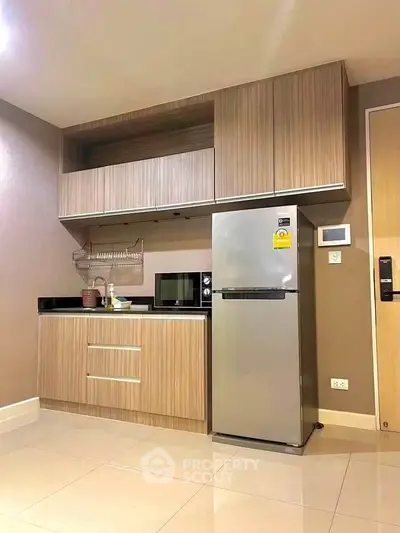 Modern kitchen with sleek cabinetry and stainless steel fridge in stylish apartment.