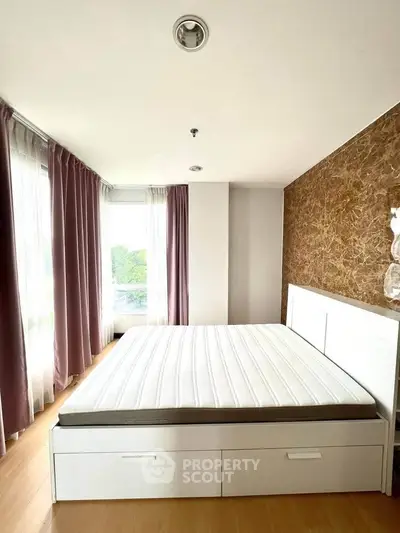 Spacious bedroom with large windows and elegant curtains, featuring a modern bed with storage drawers.