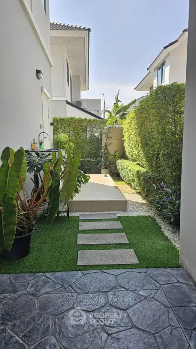 Charming garden pathway leading to modern house entrance with lush greenery