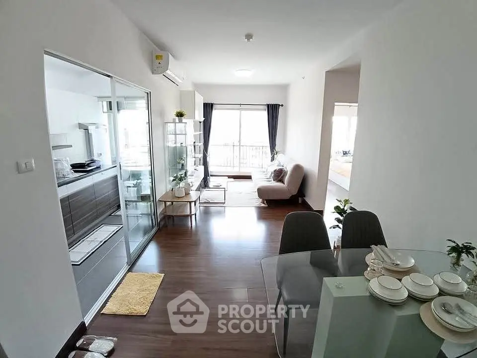 Modern open-plan living room with sleek kitchen and dining area, featuring elegant decor and natural light.