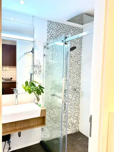 Modern bathroom with glass shower and stylish sink in contemporary apartment.