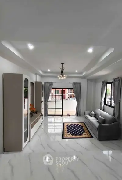 Spacious modern living room with elegant chandelier and large windows for natural light.