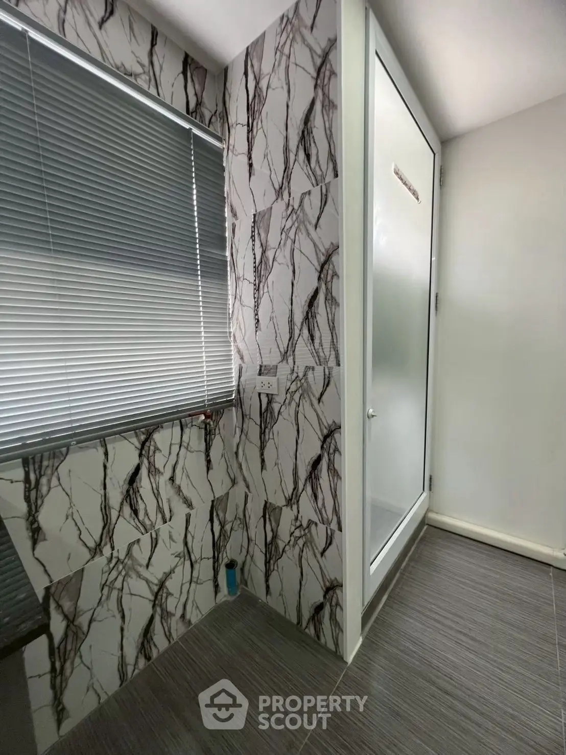 Modern bathroom with marble-patterned walls and frosted glass shower door