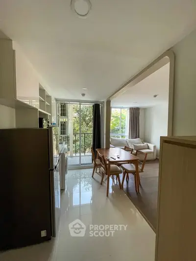 Modern open-plan living room with dining area and large windows overlooking greenery.