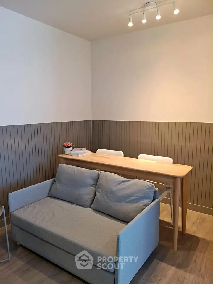 Modern living room with stylish sofa and dining table, featuring elegant wood paneling and cozy lighting.
