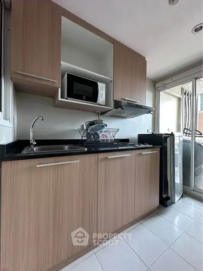 Modern kitchen with sleek wooden cabinets and stainless steel appliances in a bright apartment.