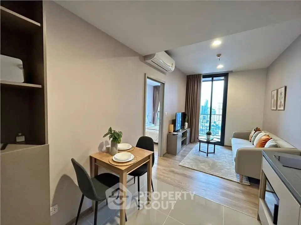 Modern open-plan living room with dining area and city view balcony in stylish apartment.