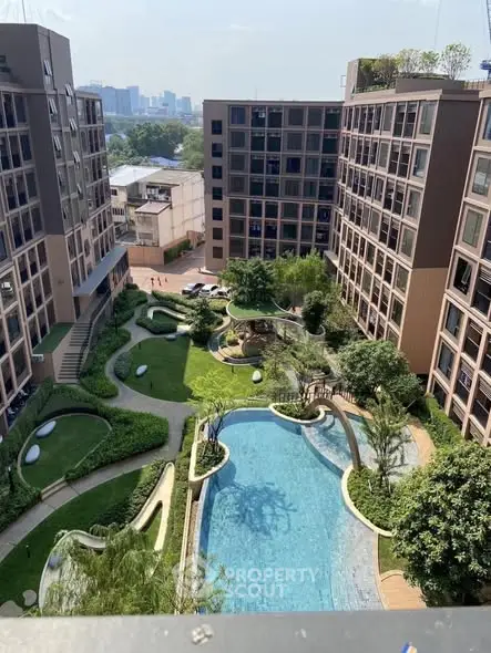Stunning aerial view of modern apartment complex with lush garden and inviting pool.