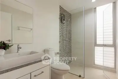 Modern bathroom with glass shower and sleek fixtures in a contemporary home.