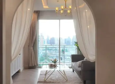 Elegant living room with city view, featuring modern decor and large windows for natural light.
