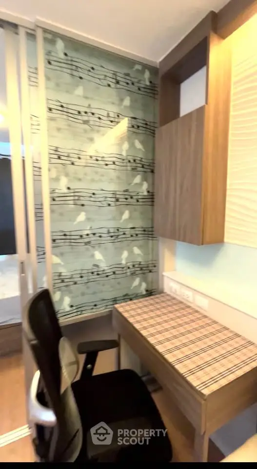 Modern study nook with stylish wallpaper and ergonomic chair in a cozy apartment.