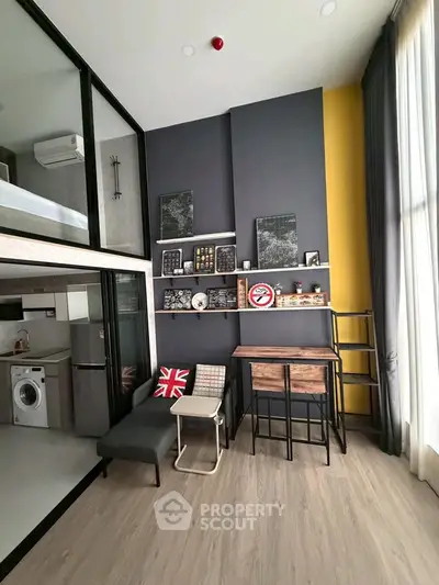Modern loft apartment with high ceilings, stylish decor, and compact kitchen featuring washing machine.