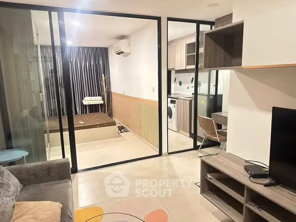 Modern apartment interior with open layout, featuring living room, kitchen, and bedroom with glass partition.