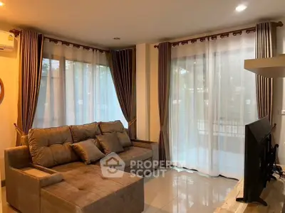 Cozy living room with plush sofa and large windows offering natural light