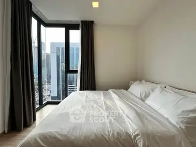 Modern bedroom with large windows offering stunning city views in a high-rise apartment.
