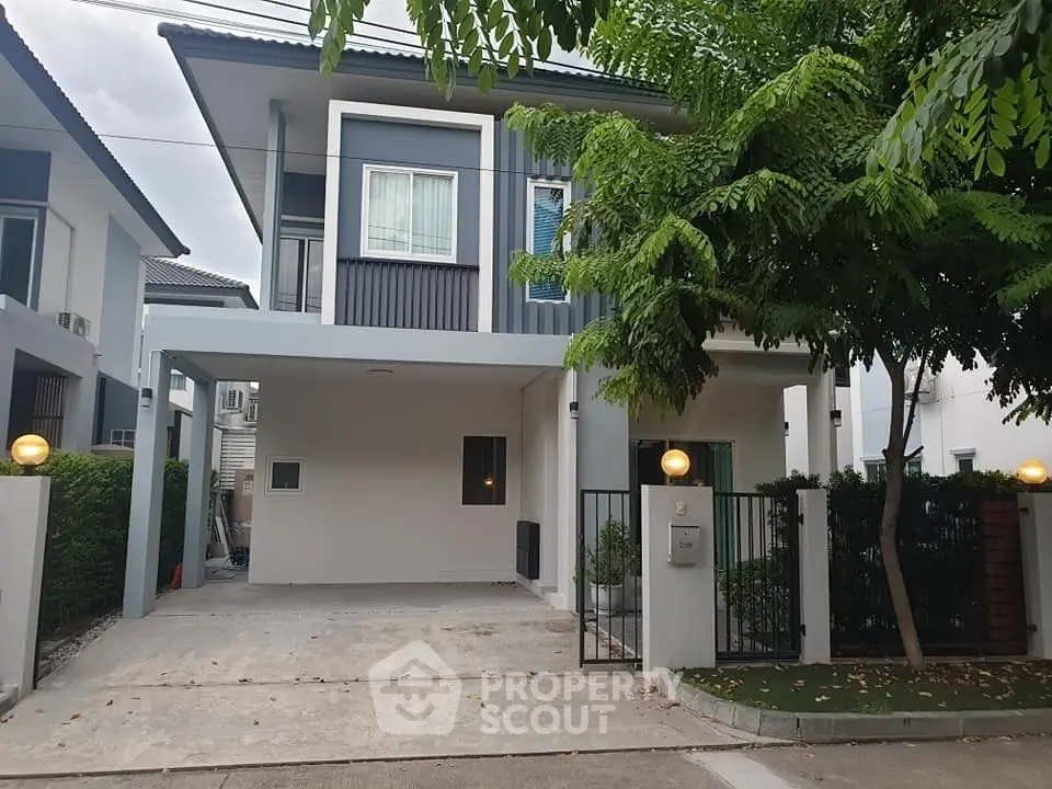 Modern two-story house with driveway and lush greenery in a serene neighborhood.