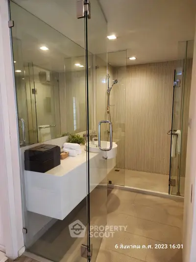Modern bathroom with glass shower enclosure and sleek vanity in luxury apartment