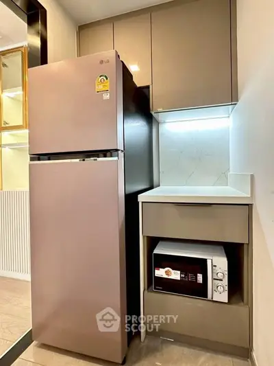 Modern kitchen with sleek fridge and microwave in compact space