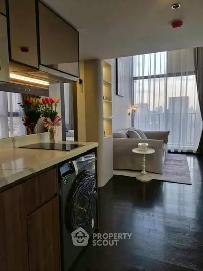 Modern open-layout living room with city view, featuring sleek kitchen and cozy seating area.