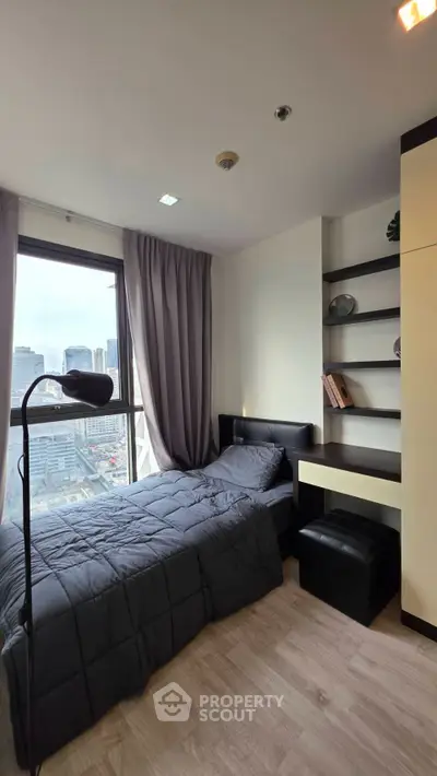 Modern bedroom with city view, featuring a cozy bed, sleek shelves, and a stylish floor lamp.