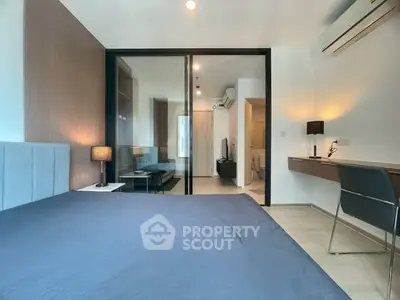 Modern bedroom with sleek design and glass partition, featuring a cozy workspace and ambient lighting.