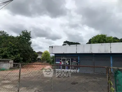 Commercial property with gated entrance and ample outdoor space under cloudy skies.