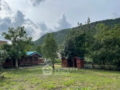 Charming rustic cabin with lush greenery and mountain backdrop, perfect for nature lovers seeking tranquility.