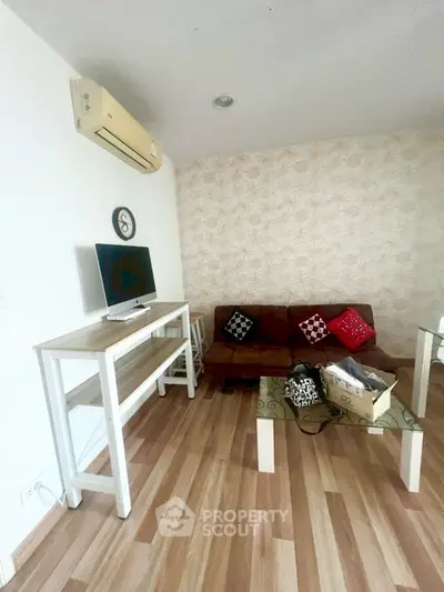 Cozy living room with modern decor and wooden flooring, featuring a stylish sofa and wall-mounted air conditioner.