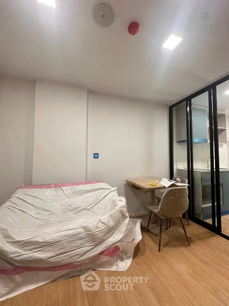 Modern apartment interior with covered furniture and compact kitchen area