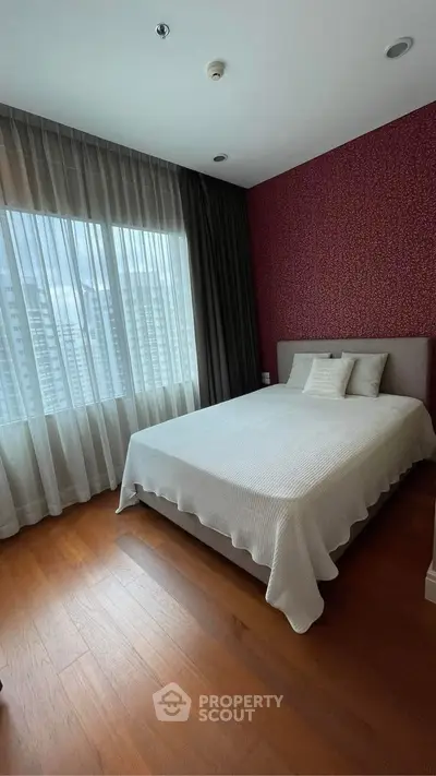 Cozy bedroom with elegant decor and large window offering city views.