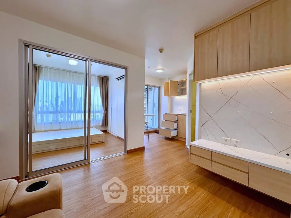 Spacious modern living room with wooden flooring and large windows offering city views.