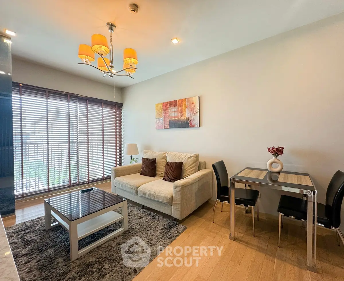 Modern living room with cozy sofa, stylish chandelier, and dining area in open layout apartment.