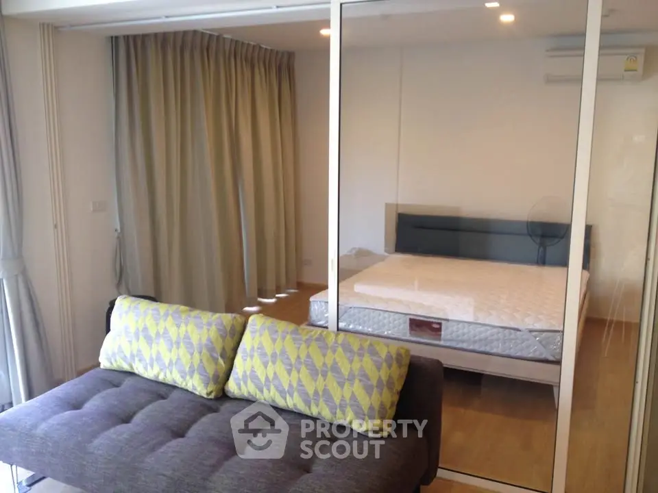 Modern studio apartment with glass partition and cozy sofa in vibrant living space.