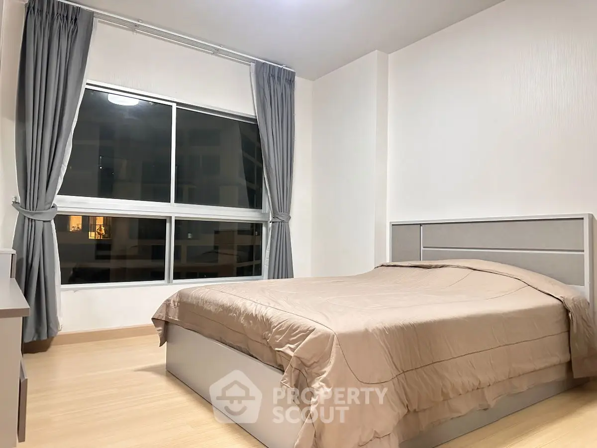 Modern bedroom with large window and stylish curtains in a cozy apartment.