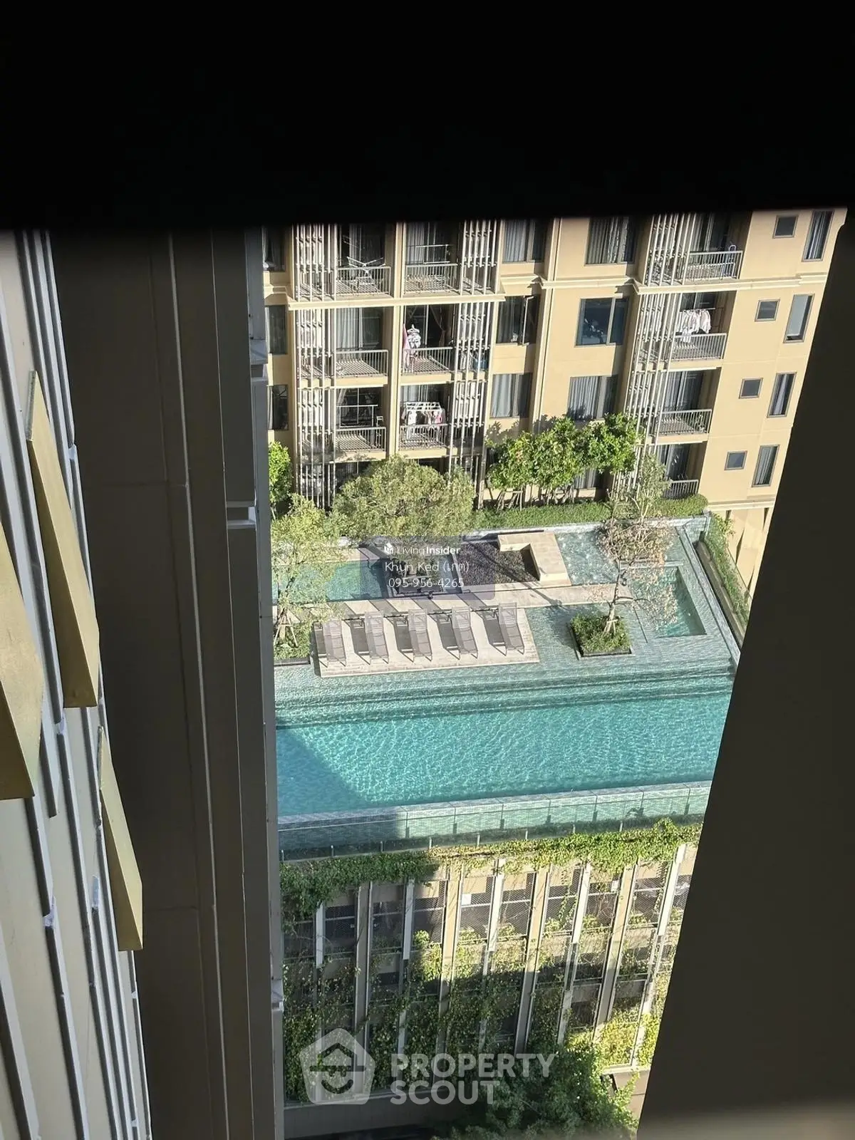 Stunning aerial view of modern apartment complex with rooftop pool and lush greenery.