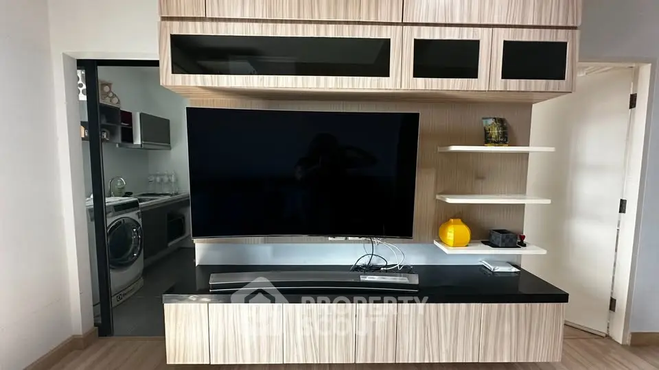 Modern living room with sleek TV unit and adjacent laundry area featuring washer and dryer.