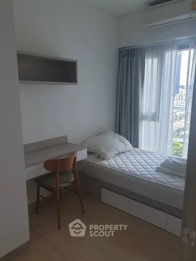 Cozy bedroom with a city view, featuring a single bed and study desk, perfect for urban living.