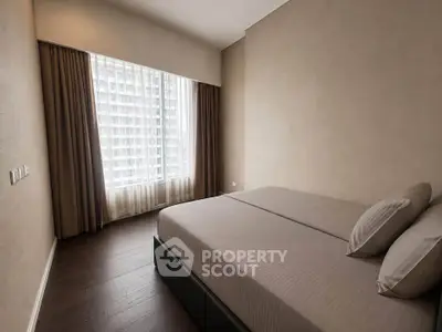 Modern bedroom with large window and neutral decor in a high-rise apartment.