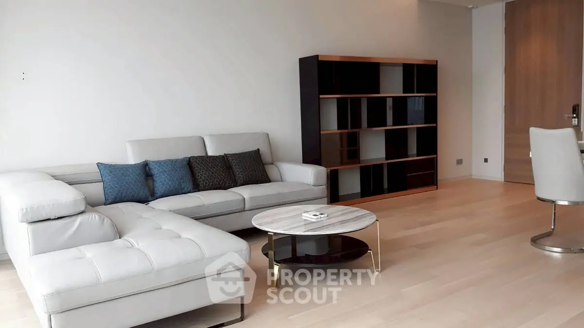Spacious modern living room with elegant white sectional sofa and sleek bookshelf.