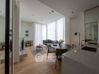 Modern living room with open layout, featuring sleek furniture and large windows for natural light.