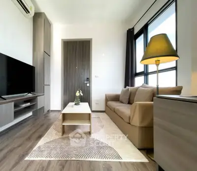 Modern living room with cozy sofa, stylish lamp, and large TV in a bright apartment.