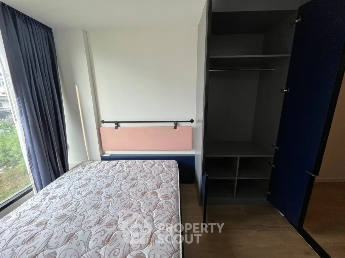 Modern bedroom with large window and built-in closet, offering ample natural light and storage space.