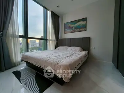 Spacious bedroom with large windows and modern decor in urban apartment.