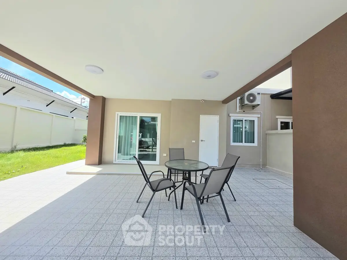 Spacious modern patio with outdoor seating and lush green lawn, perfect for relaxation and entertainment.