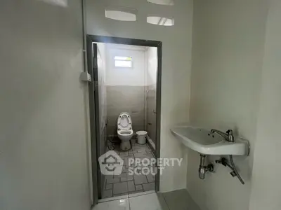 Compact bathroom with modern fixtures and neutral tiles, featuring a wall-mounted sink and toilet.