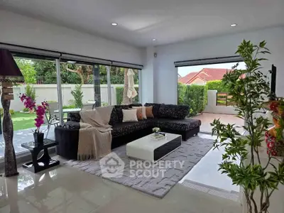 Spacious modern living room with large windows and garden view, perfect for relaxation and entertaining.