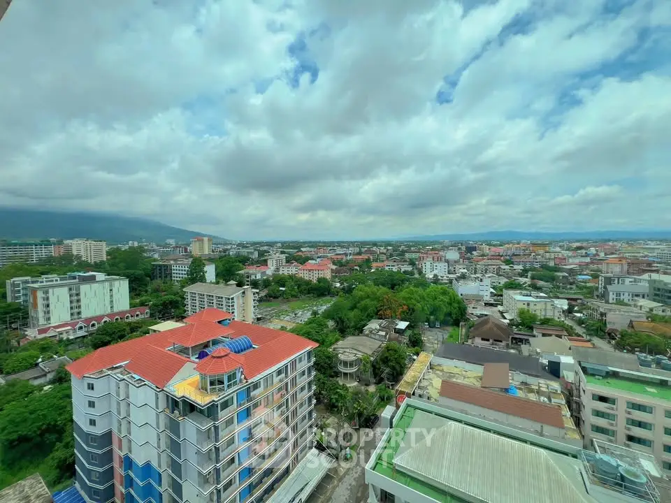 Stunning aerial view of cityscape with vibrant buildings and lush greenery under a cloudy sky.