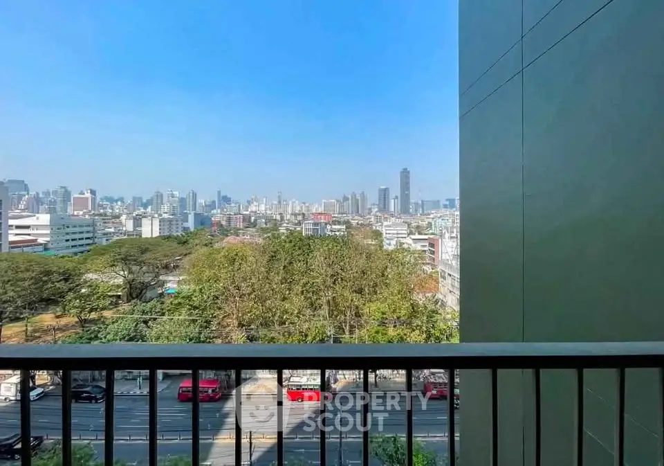 Stunning cityscape view from a high-rise balcony overlooking urban skyline and lush greenery.