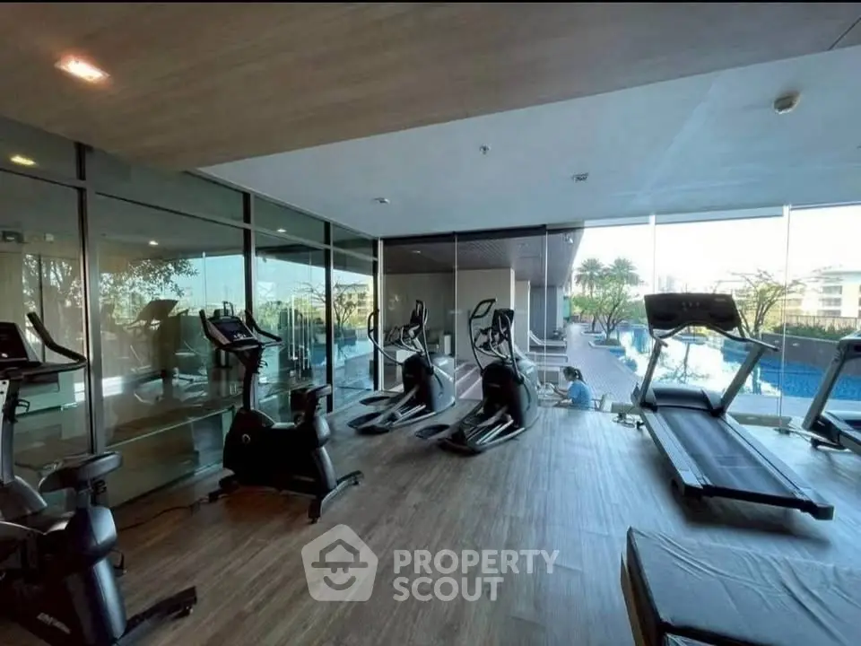 Modern gym with state-of-the-art equipment and pool view in luxury residential complex.